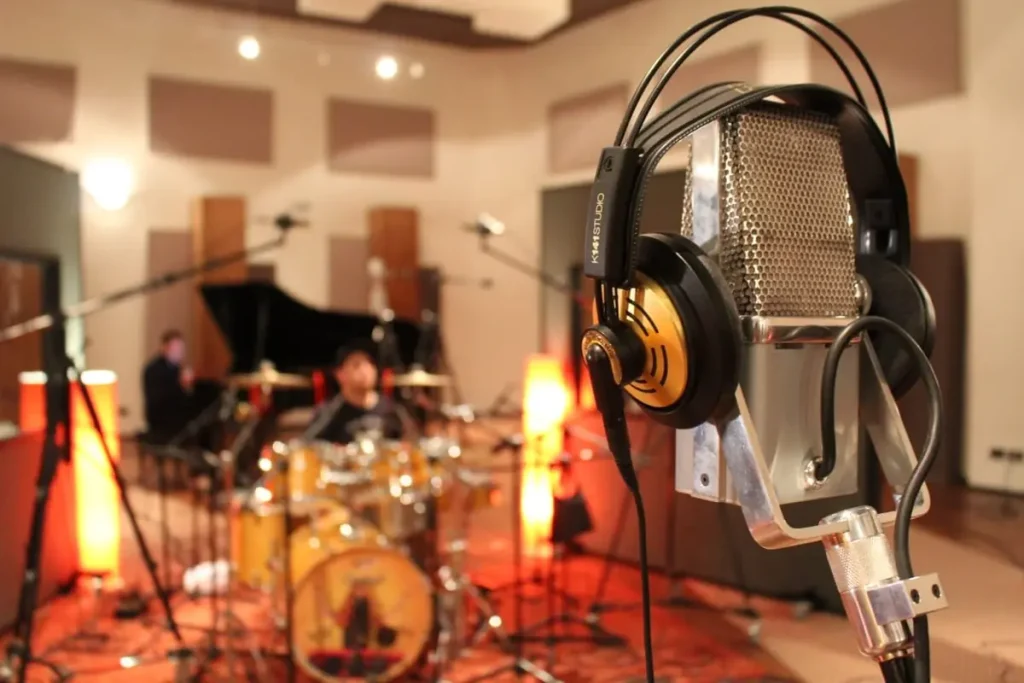 Studio microphone with a drum kit set up for recording in the background